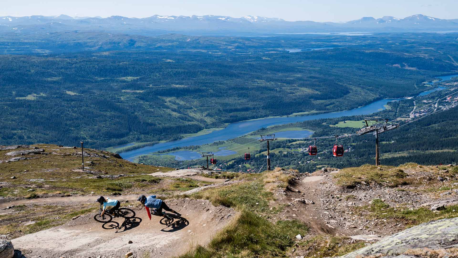 Två downhillcyklister cyklar nedför Åreskutan i strålande sol