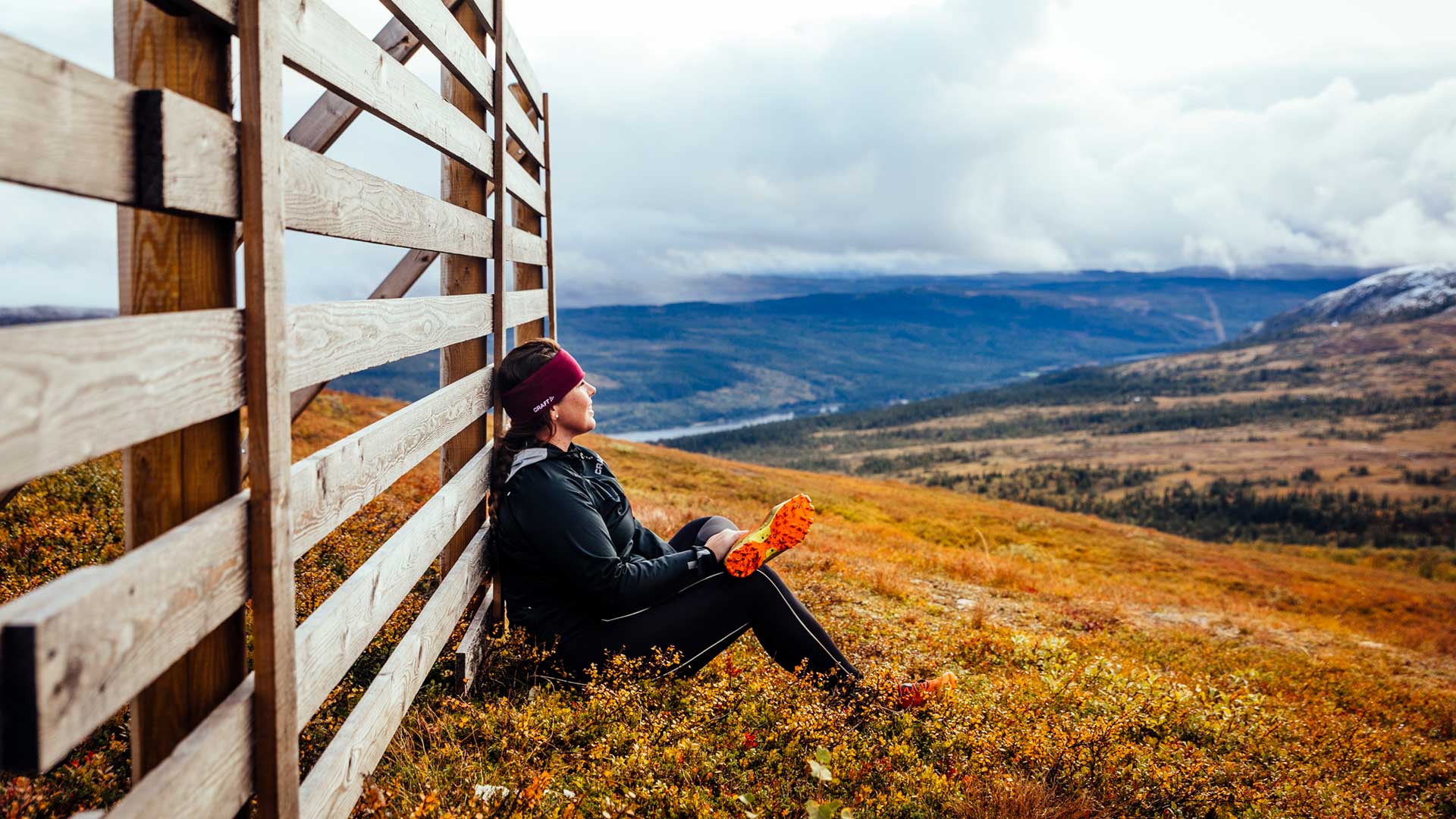 Autumn in the Åre mountains—a woman sitting by a fence, taking in the view.