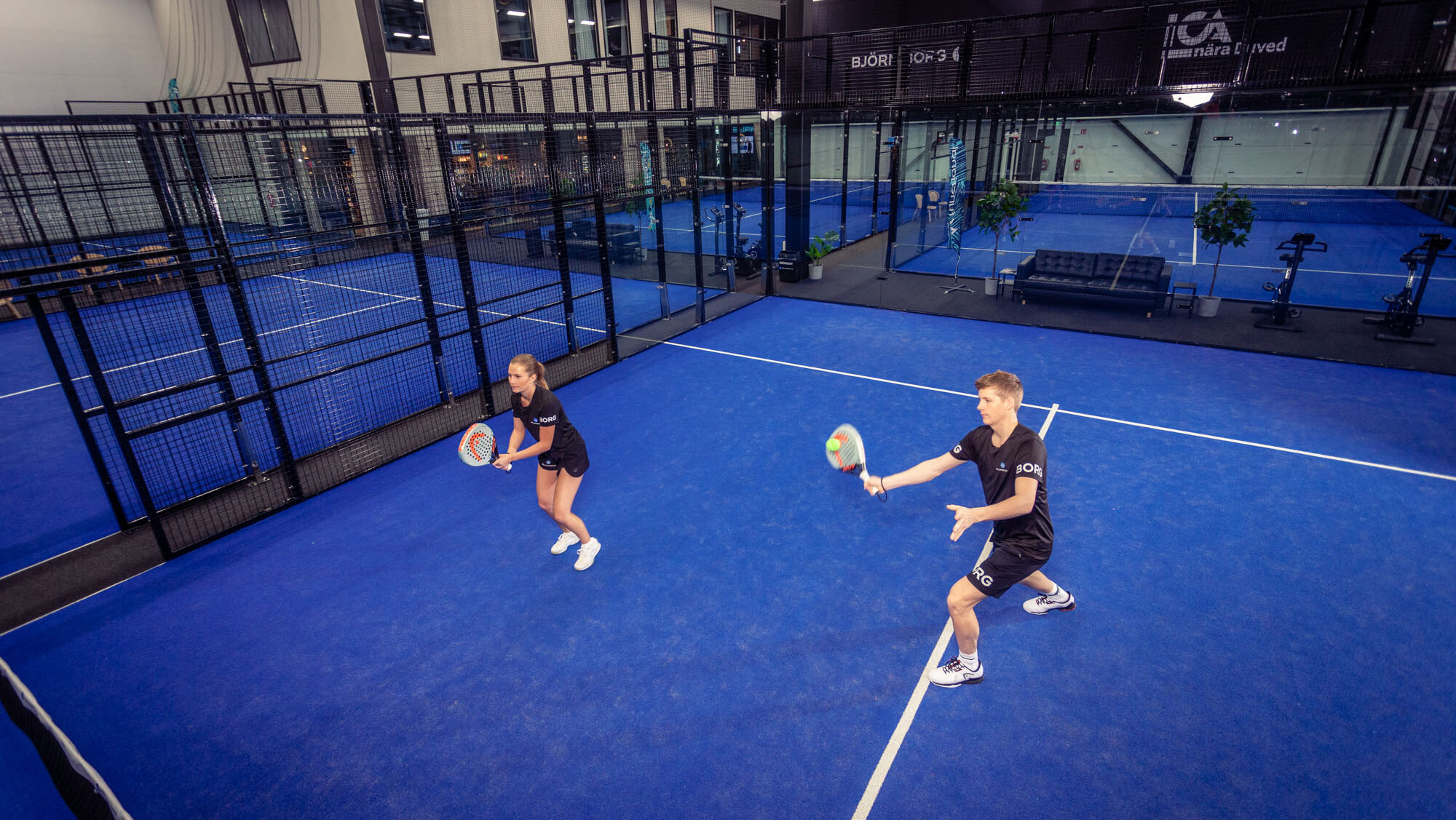 Två personer spelar padel inomhus.