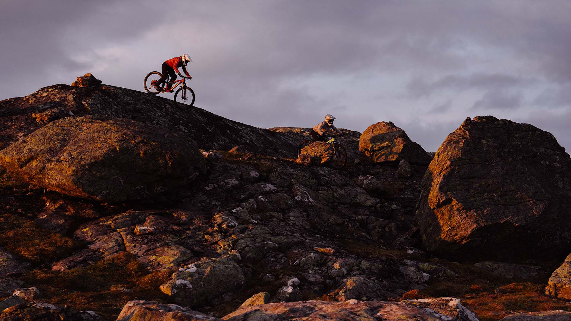 Downhillcyklist cyklar i full fart över fjällkant.