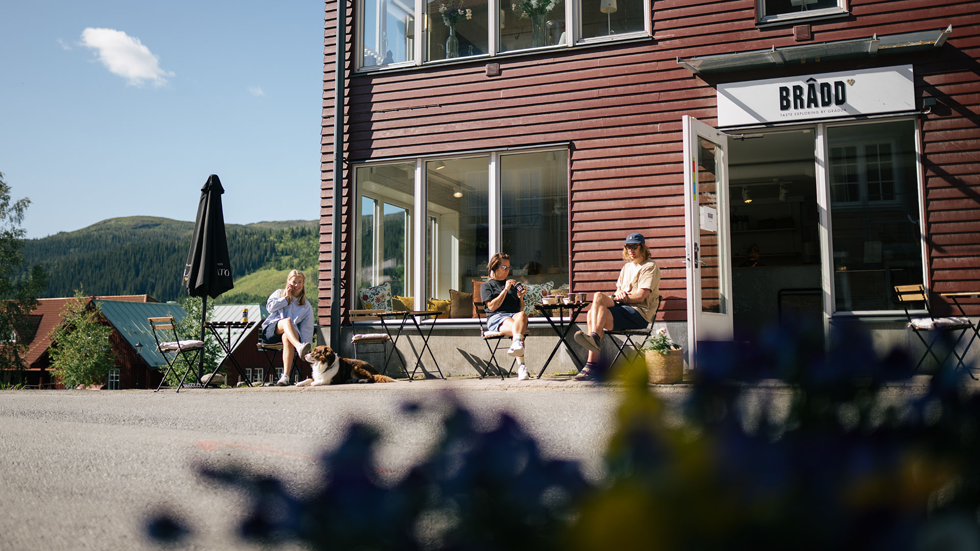Människor sitter på uteservering vid Brâdd en solig sommardag i Åre.