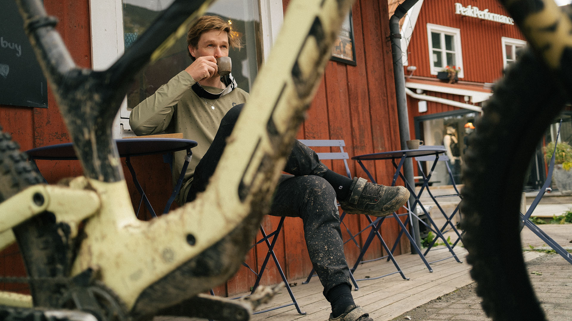 A cyclist enjoys a coffee at Åre Kafferosteri after a muddy ride.
