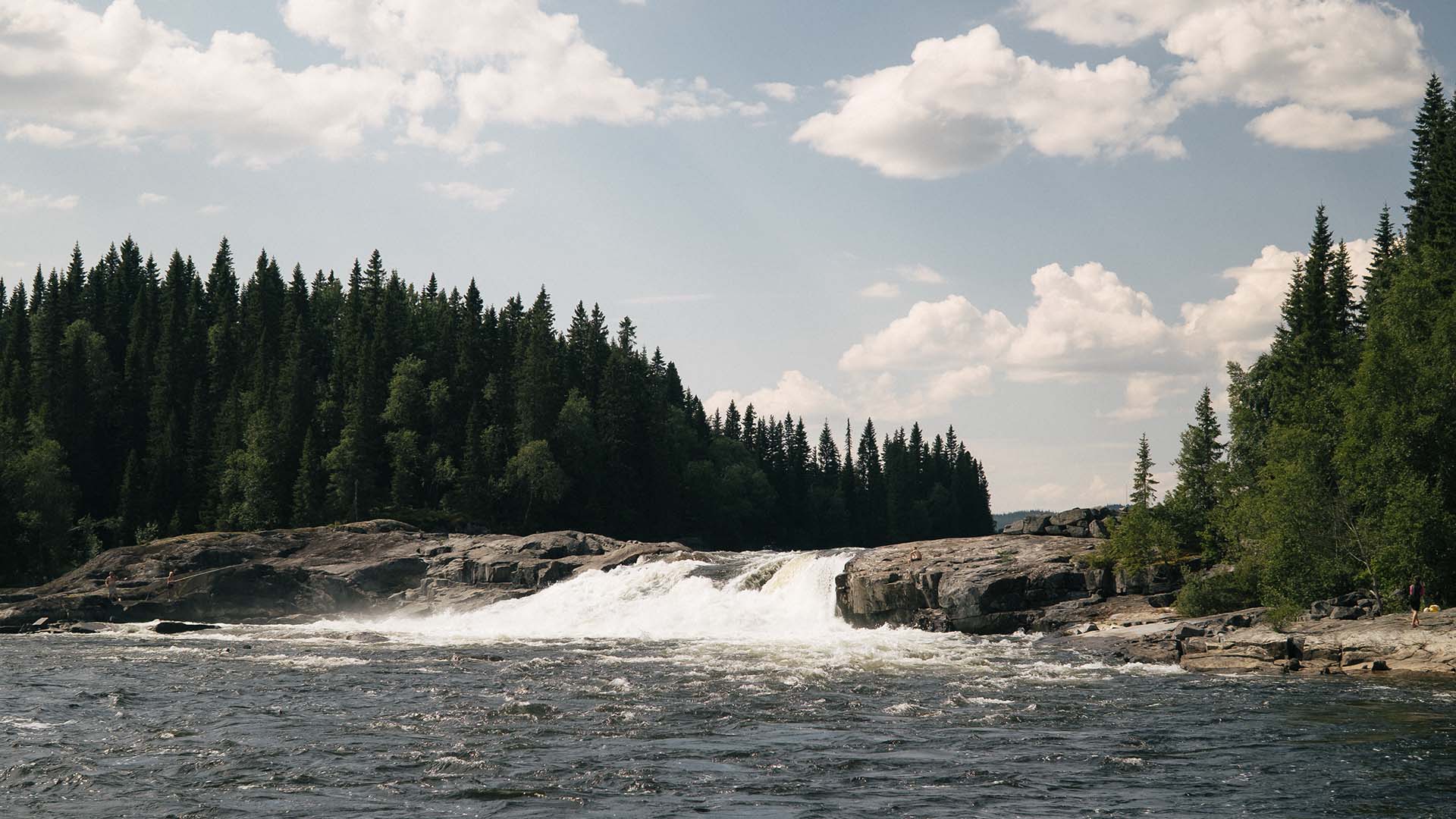 Tegeforsen på sommaren med forsande vatten och blå himmel.