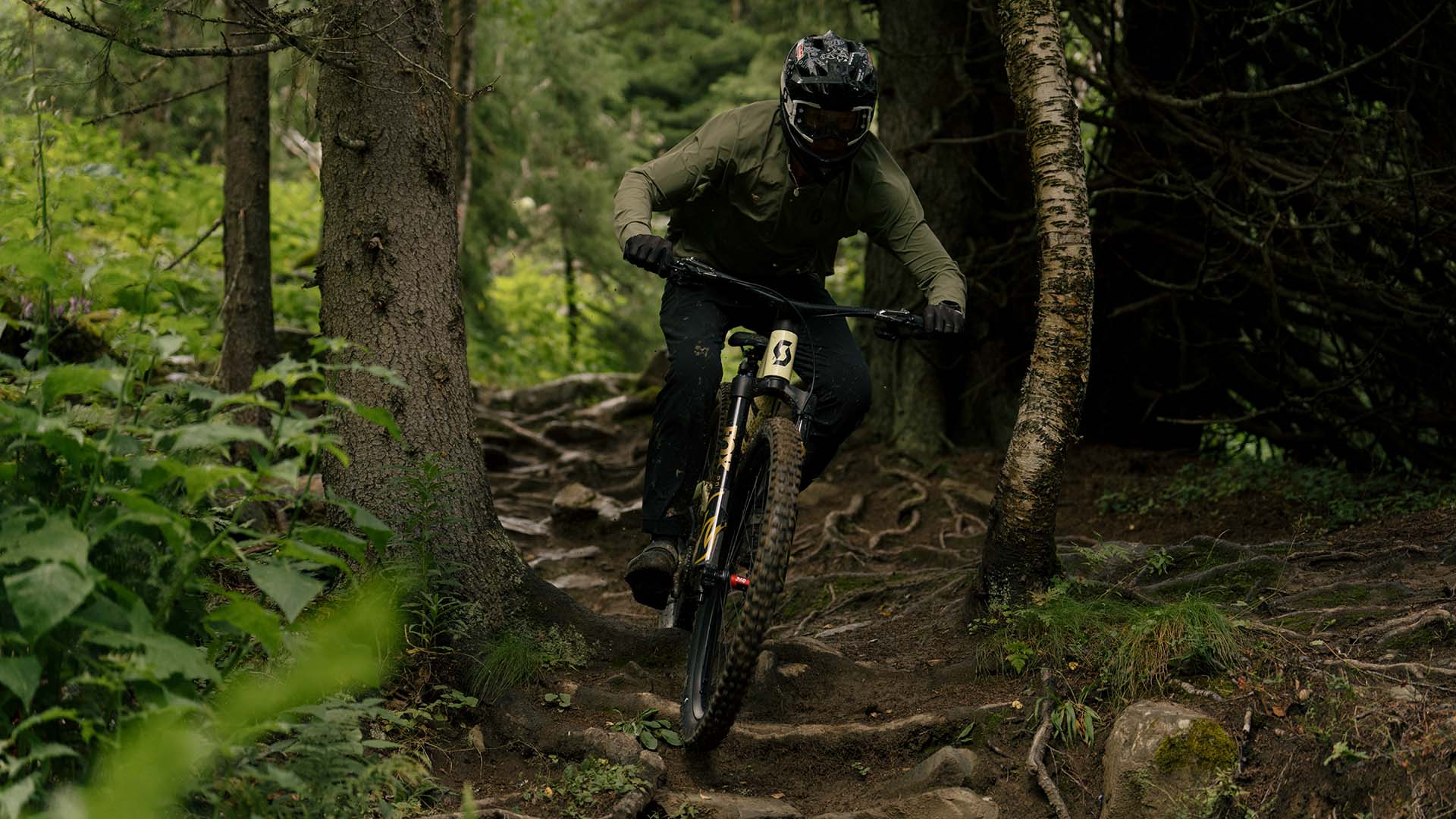 Närbild på cyklist som rullar över stenar och rötter i Åre Bike Park.