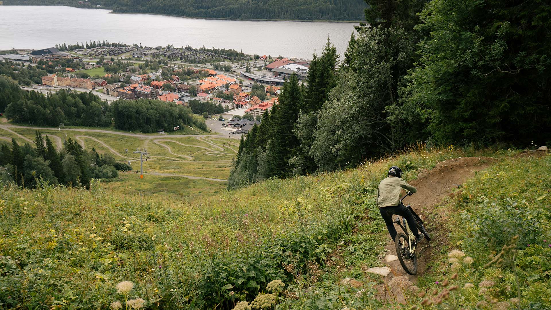 Cyklist cyklar i Åre Bike Park med utsikt mot Åre by.