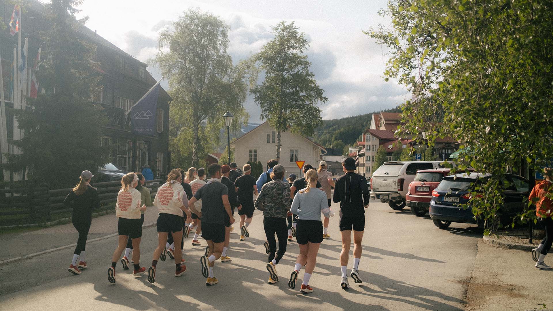 A group of runners passing by Åregården in sunlight.