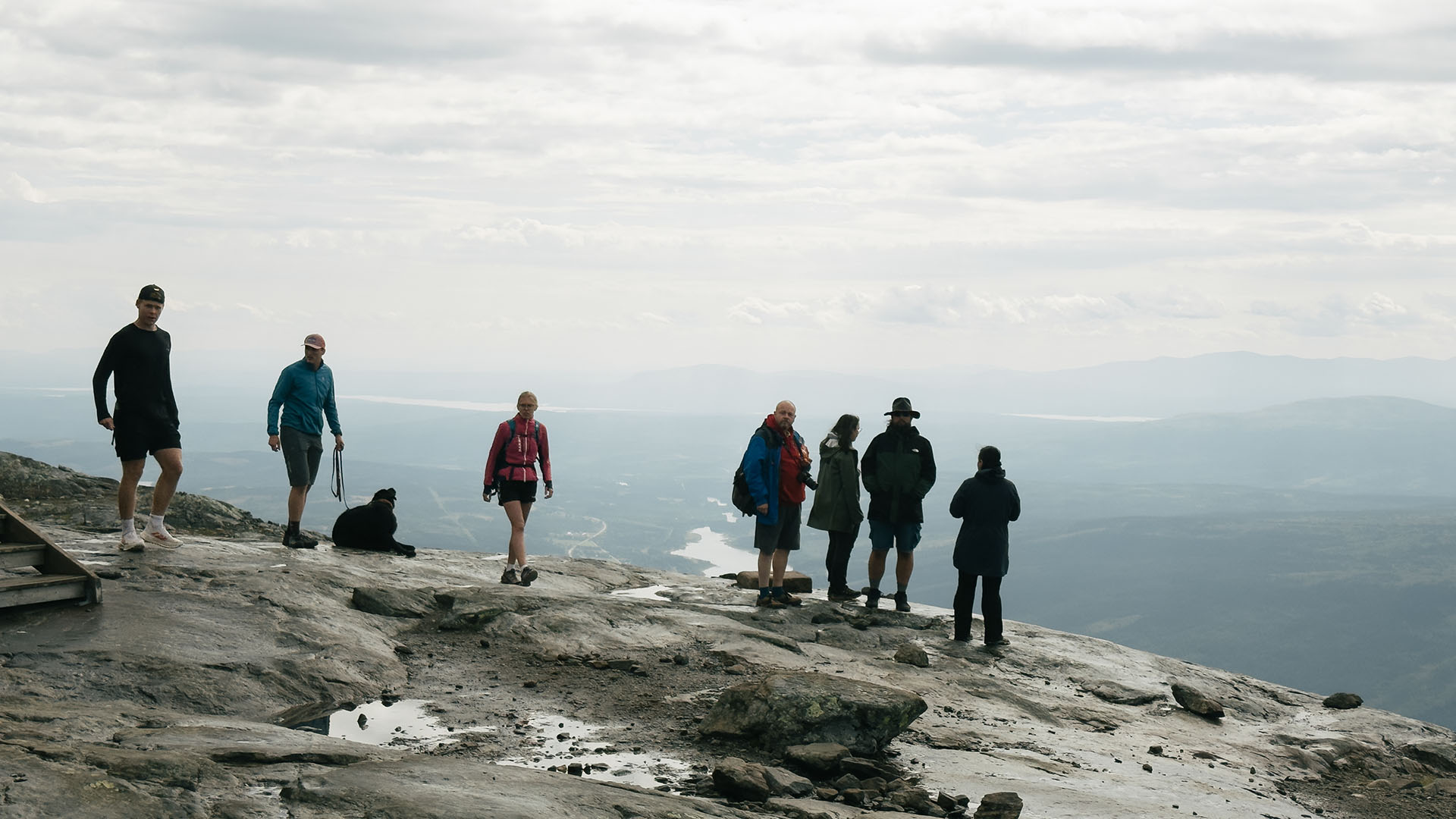 Grupp människor står på toppen av Åreskutan en gråtung sommardag.