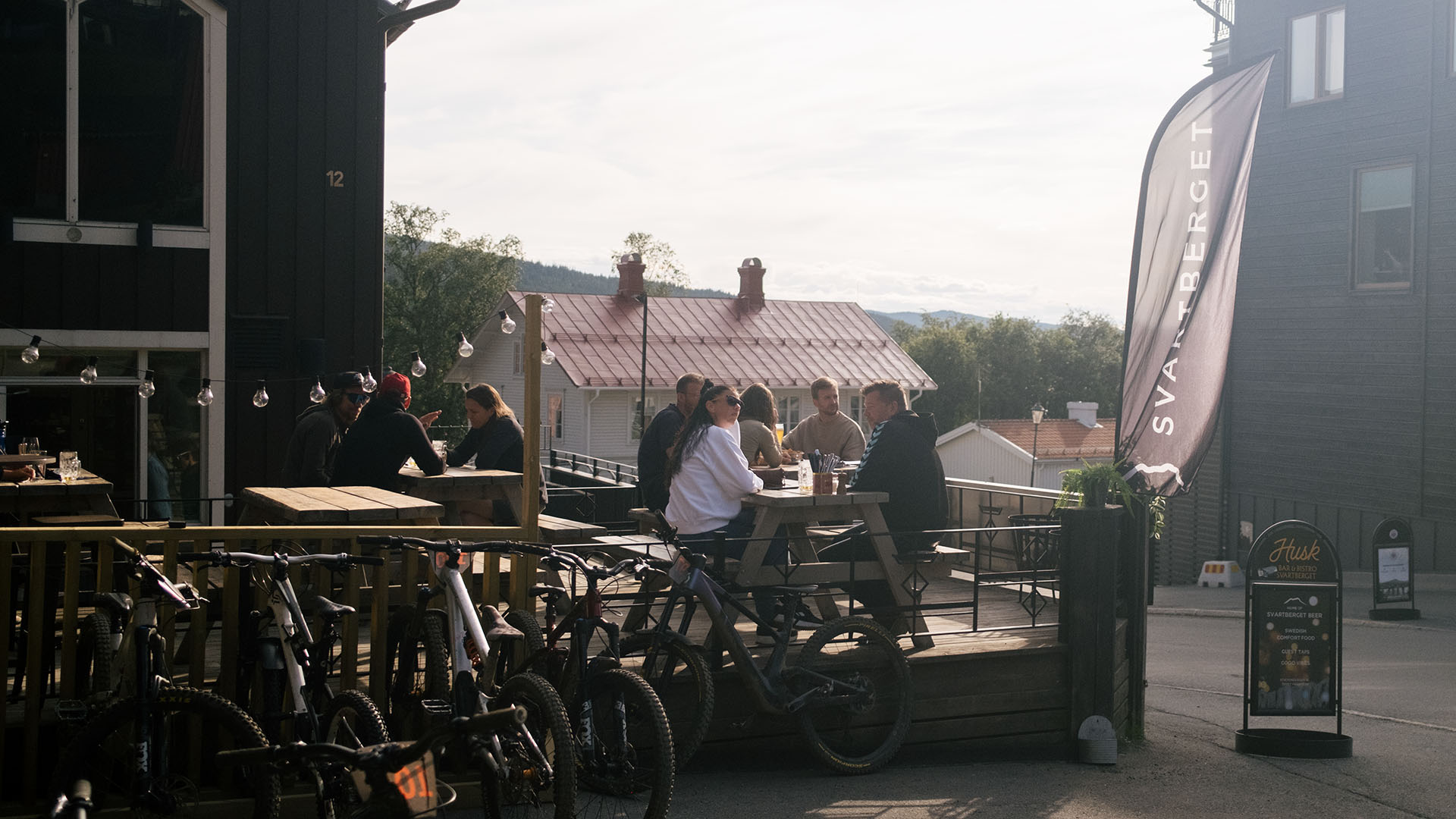 Samling människor på Husk uteservering med välfyllt cykelställ bredvid.