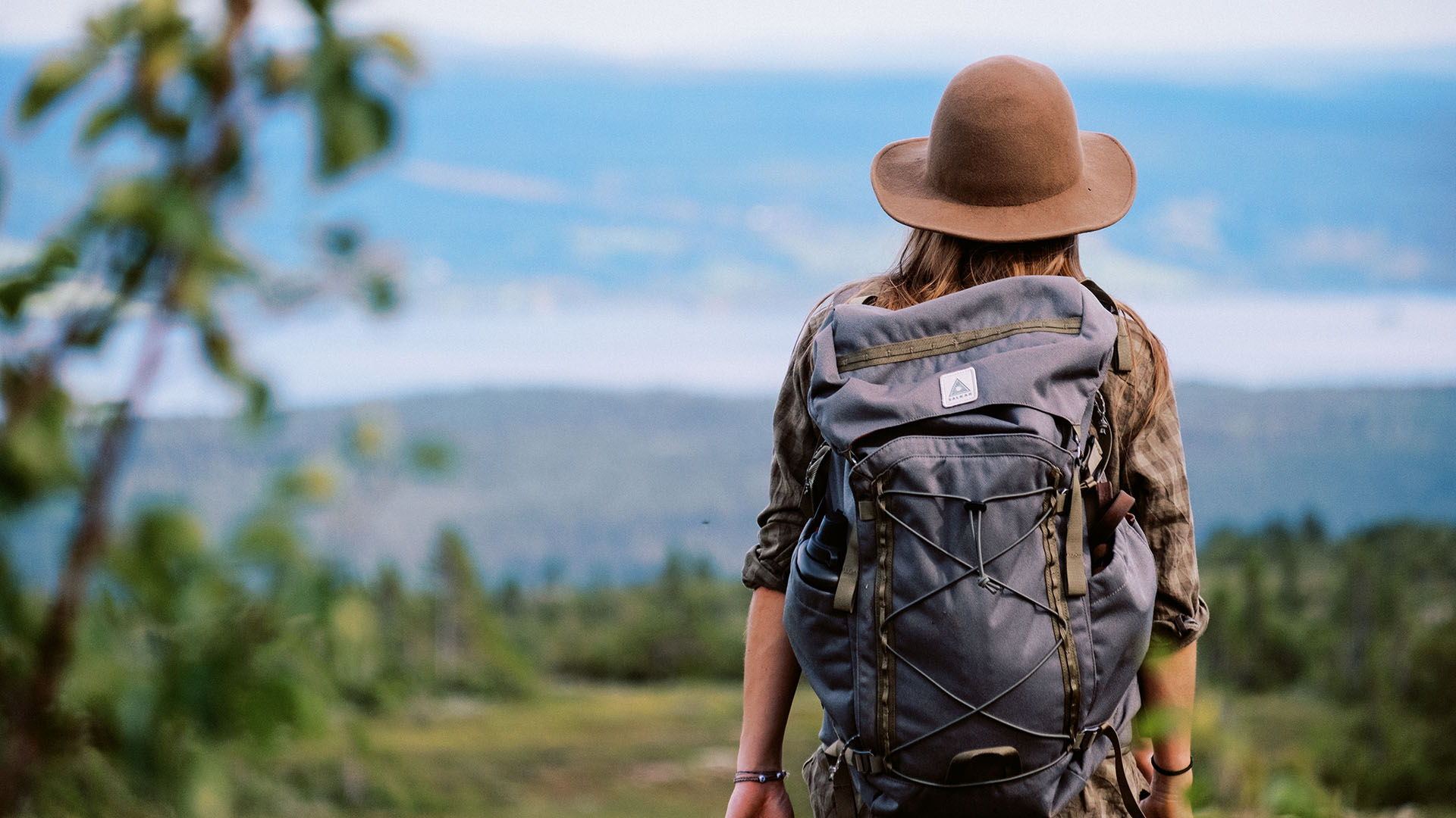 Woman in a felt hat taking in the sweeping mountain views.