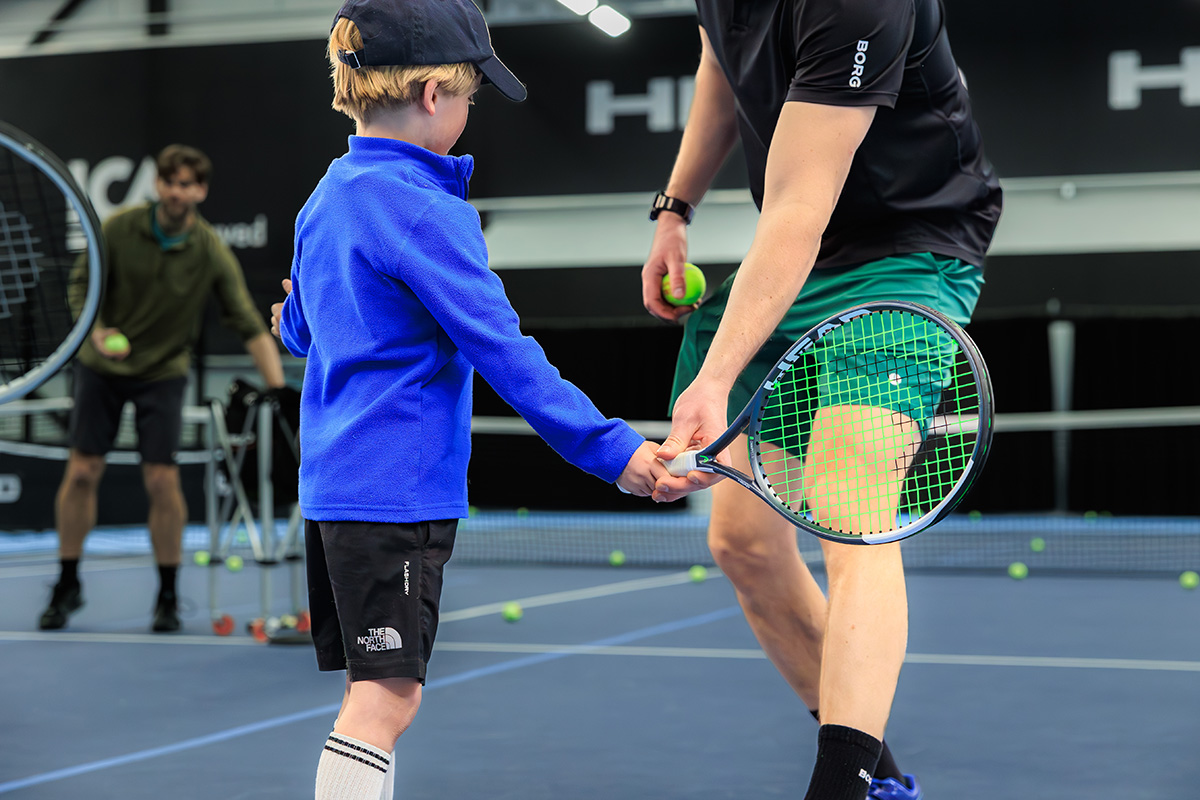 A tennis instructor teaching a child tennis skills.