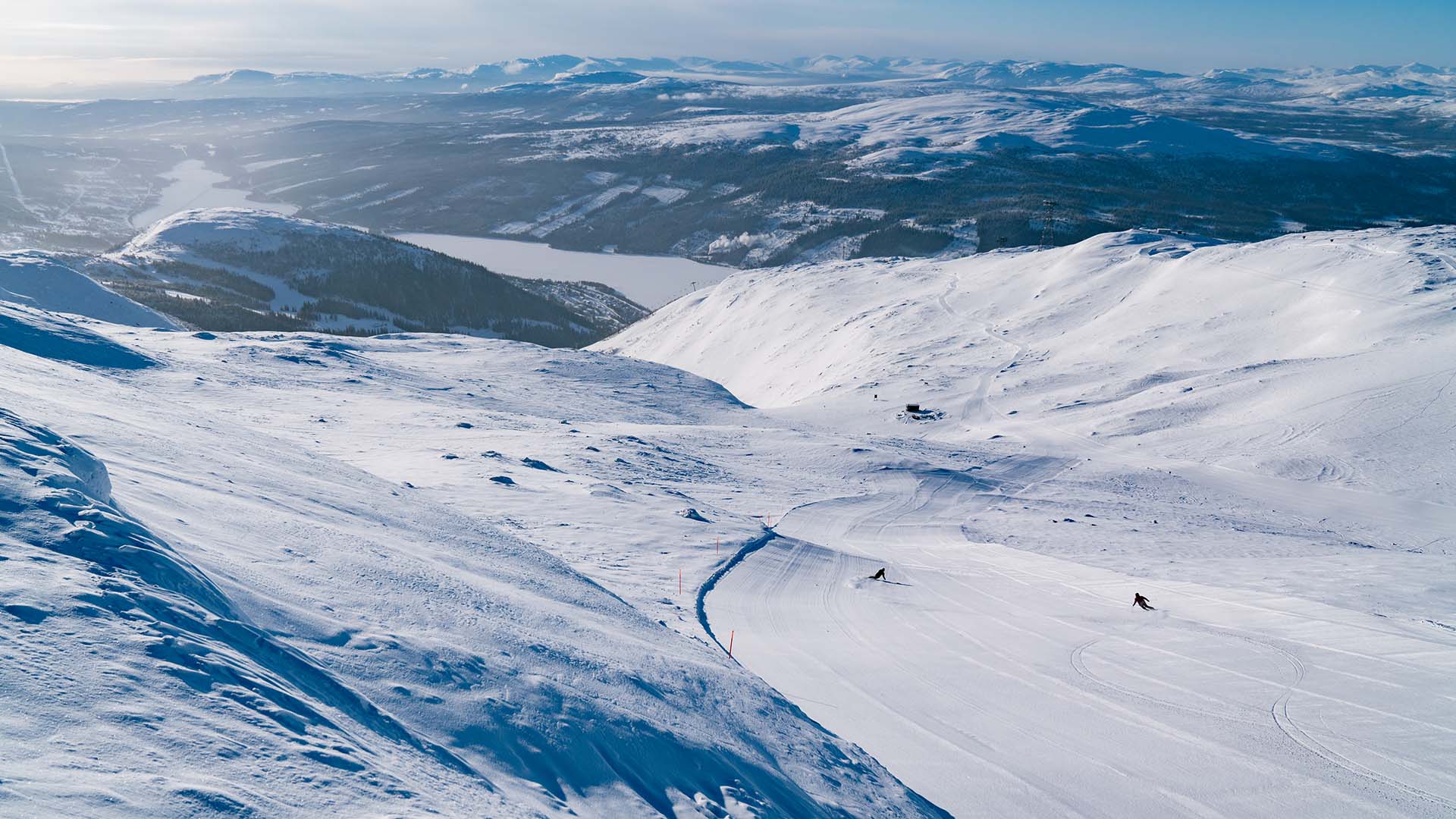 Pistad skidbacke i Åre på högzon en kall dag i januari, med utsikt över många fjäll.